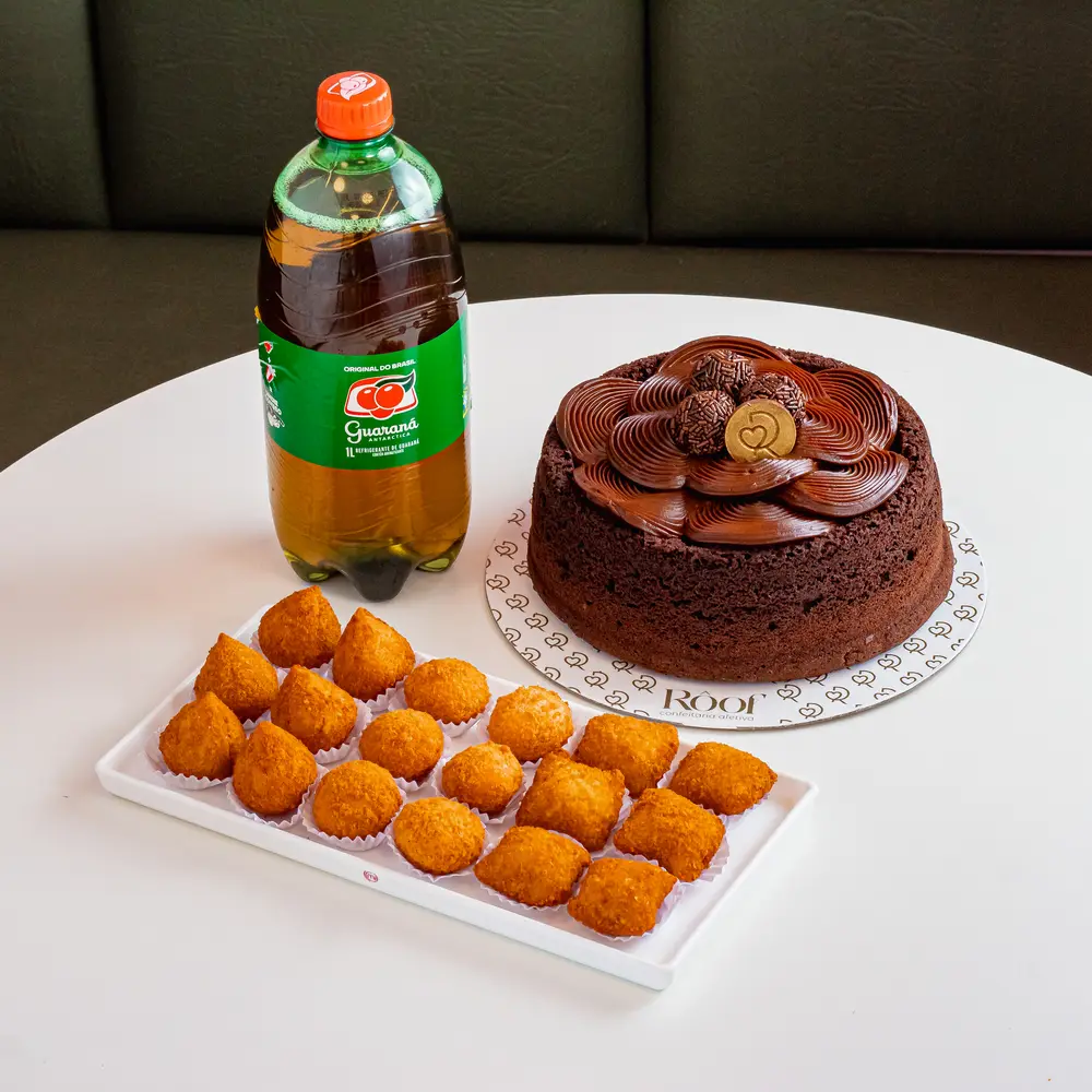 Bolo de chocolate com coxinhas e guaraná sobre a mesa, um kit pronto para a comemoração